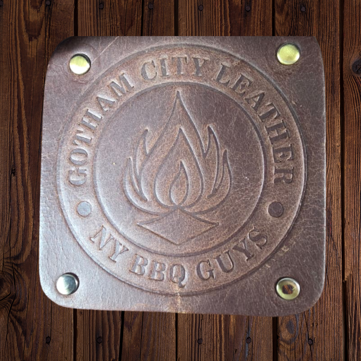 Leather with 'Gotham City Leather NY BBQ Guys' branding on a wooden background