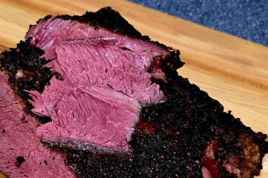 Beef rib pastrami with black pepper coriander crust and pink smoke ring on wooden cutting board - NY BBQ Guys signature recipe