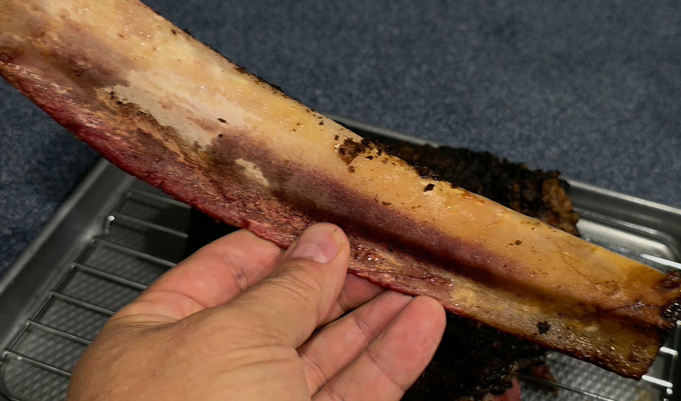 Beef rib pastrami bone pull showing fall-off-the-bone tenderness and pink smoke ring - NY BBQ Guys recipe success indicator