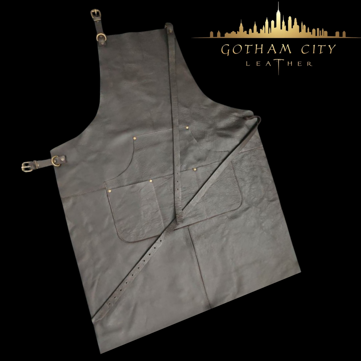 Black full-grain leather apron with brass hardware and cross-back straps, displayed on a black background with the Gotham City Leather logo above.